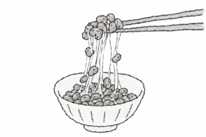 箸で納豆を持ち上げて糸を引かせる様子